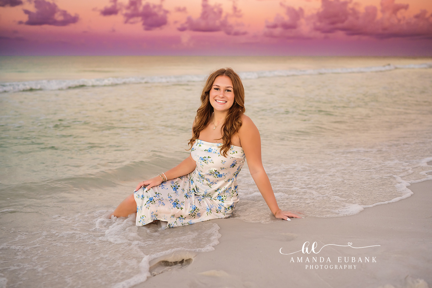 Seated in the Emerald Shallows | Tampa Senior Photographer A senior in a floral dress seated in the emerald shallows at dusk during a senior portrait session in Tampa, Florida.