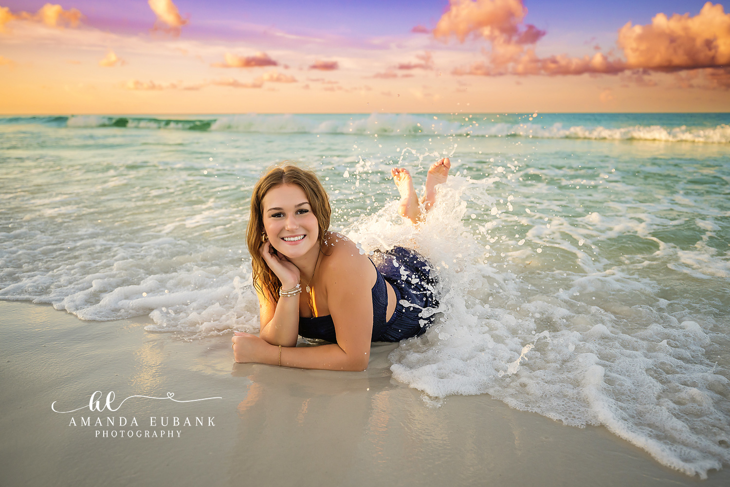 Splash in the Breaking Wave — Tampa Bay Senior Photography A senior lying on the sand as a wave crashes over her legs at sunset at a beach senior session in Tampa, FL.