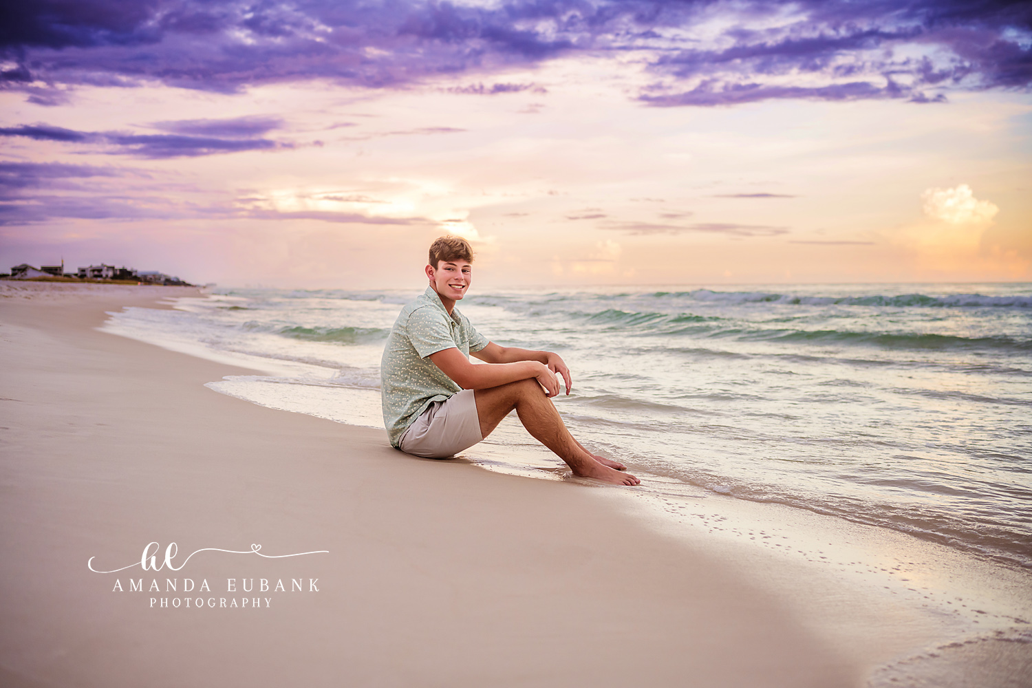 Senior Guy Seated on the Sand | Senior Portraits in Tampa, FL Tampa senior photographer captures a senior guy seated on the sand with the Gulf and sunset clouds behind him.