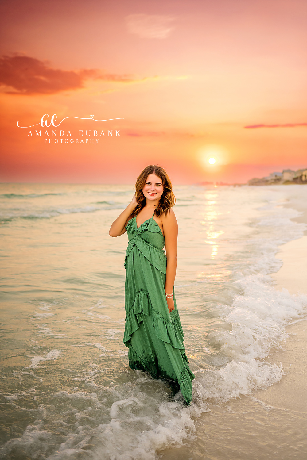 Standing at the Setting Sun | Senior Portraits in Tampa, FL Tampa senior photographer captures a senior in a green gown standing in the surf as the sun touches the water.