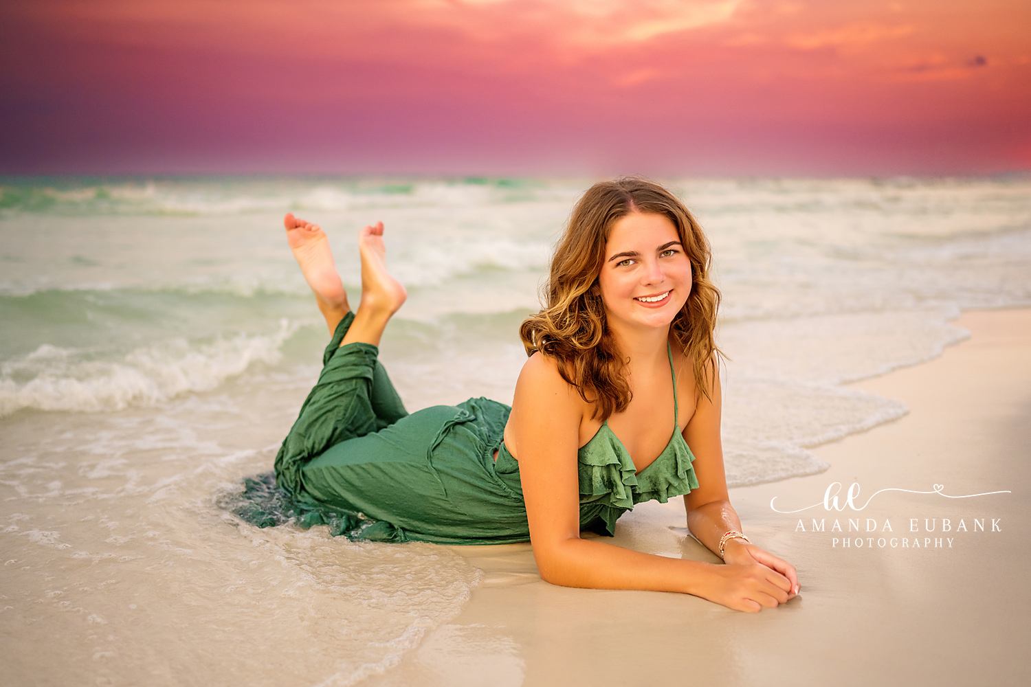 Green Gown on the Wet Sand | Senior Portraits in Tampa, FL Tampa senior photographer captures a laughing senior in a green gown lying on the wet sand under a pink sky.