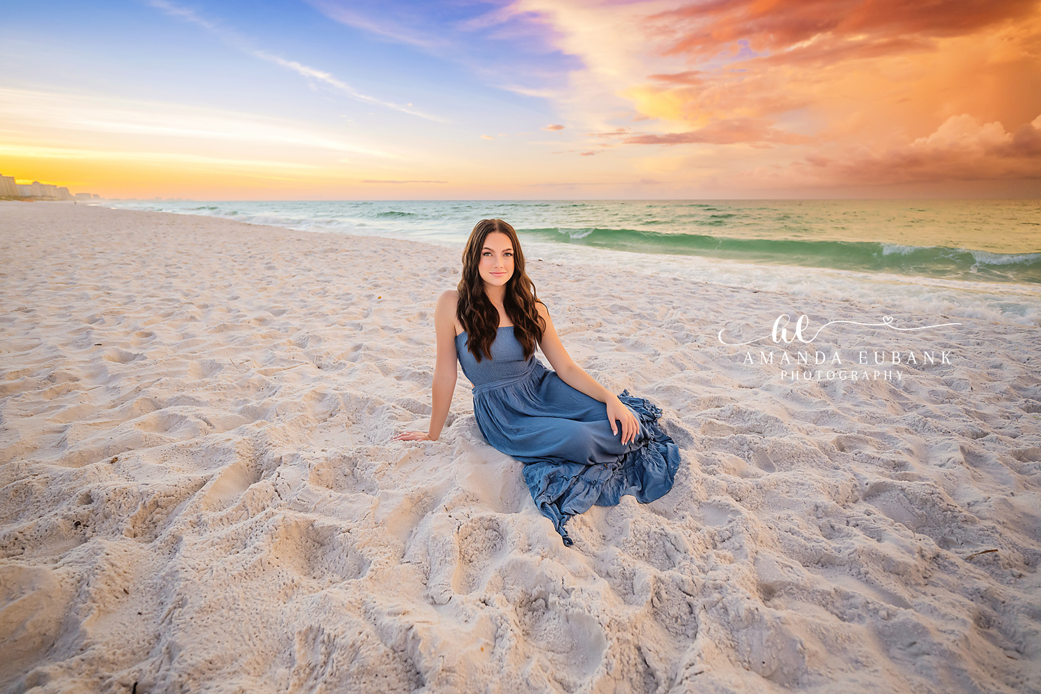 Blue Gown on Open Sand | Tampa Senior Photographer A senior in a blue gown seated on open white sand under a wide golden sky during a senior portrait session in Tampa, Florida.