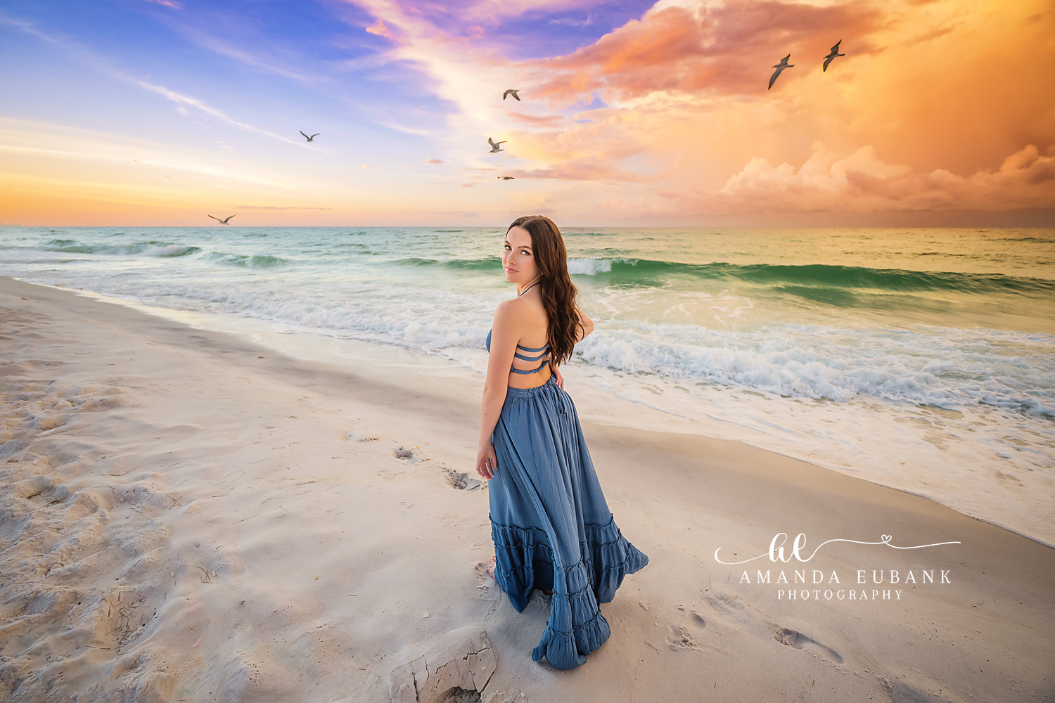 Gulls and a Blue Gown | Beach Senior Session in Tampa, Florida Senior pictures in Tampa Bay showing a senior in a blue gown on the shoreline as gulls fly past at sunset.