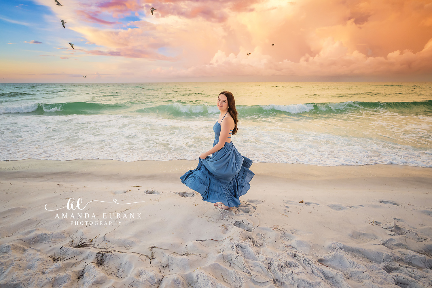 Wind and Waves Senior Portrait — Tampa Bay Senior Photography A senior in a windblown blue gown standing before the breaking surf at a beach senior session in Tampa, FL.