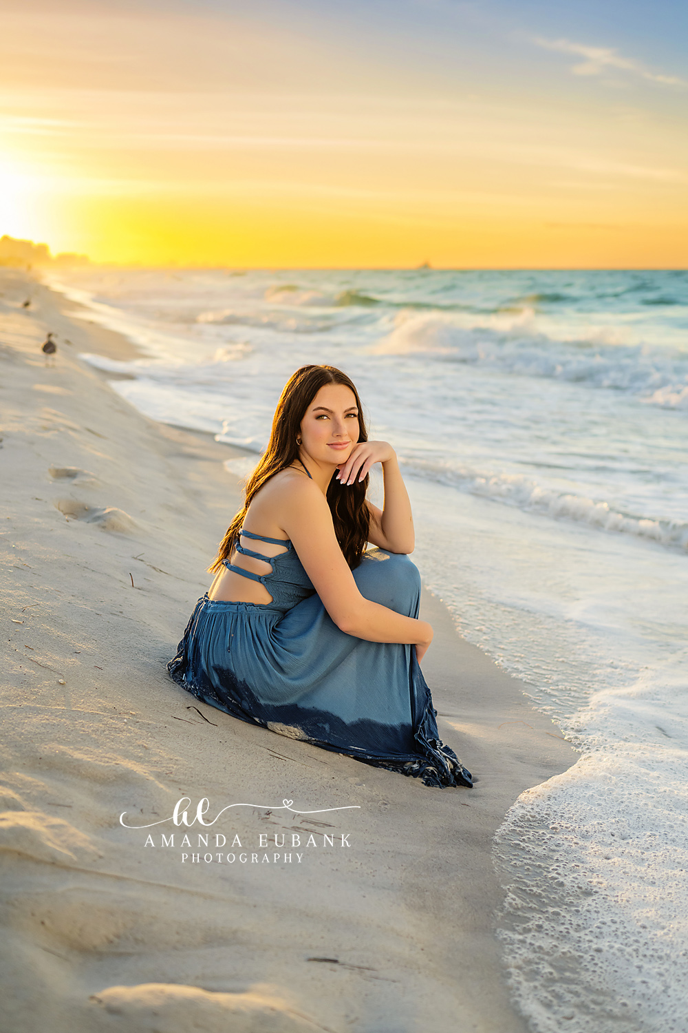 Golden Hour Blue Skirt | Tampa Senior Photographer A senior in a blue skirt seated by the surf as the sky glows soft gold during a senior portrait session in Tampa, Florida.