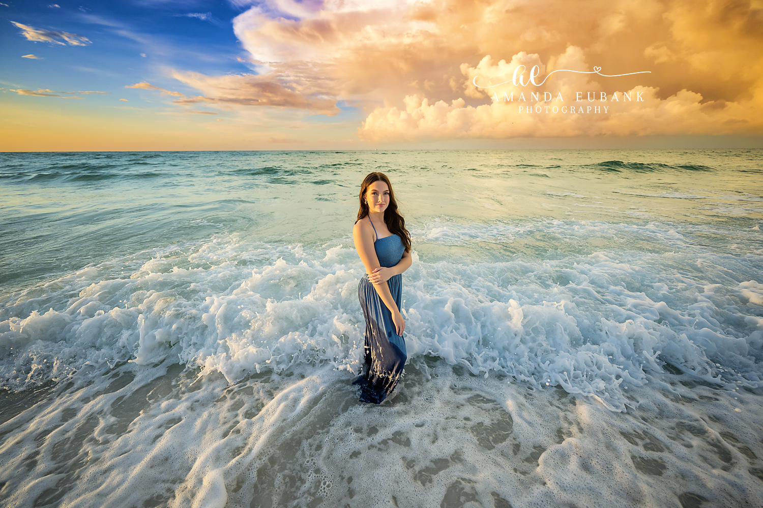 Standing in the White Water — Tampa Bay Senior Photography A senior in a navy gown standing in churning white water under big clouds at a beach senior session in Tampa, FL.
