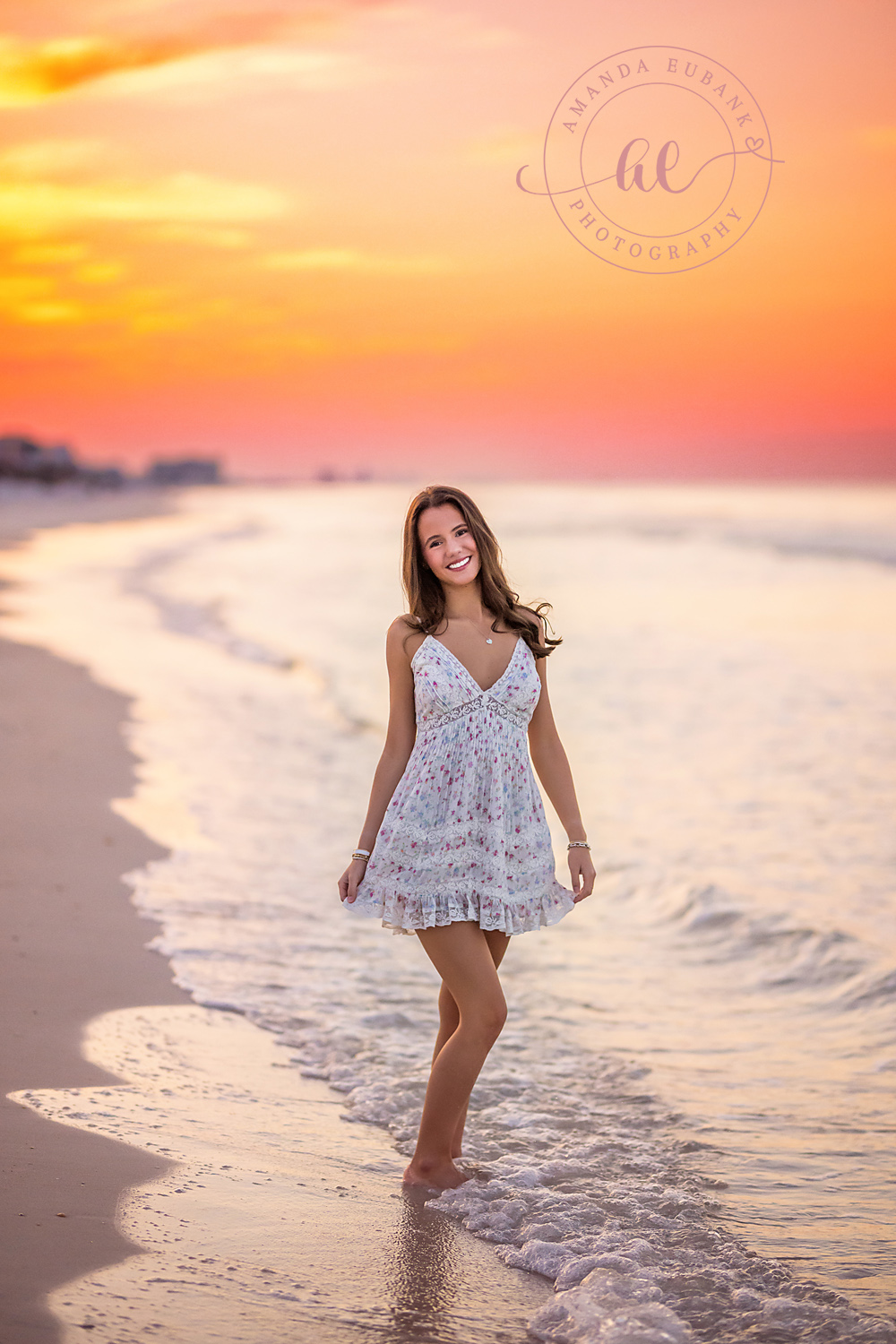 Walking the Shoreline in Lace | Senior Portraits in Tampa, FL Tampa senior photographer captures a senior in a white lace dress walking the shoreline under an orange sky.