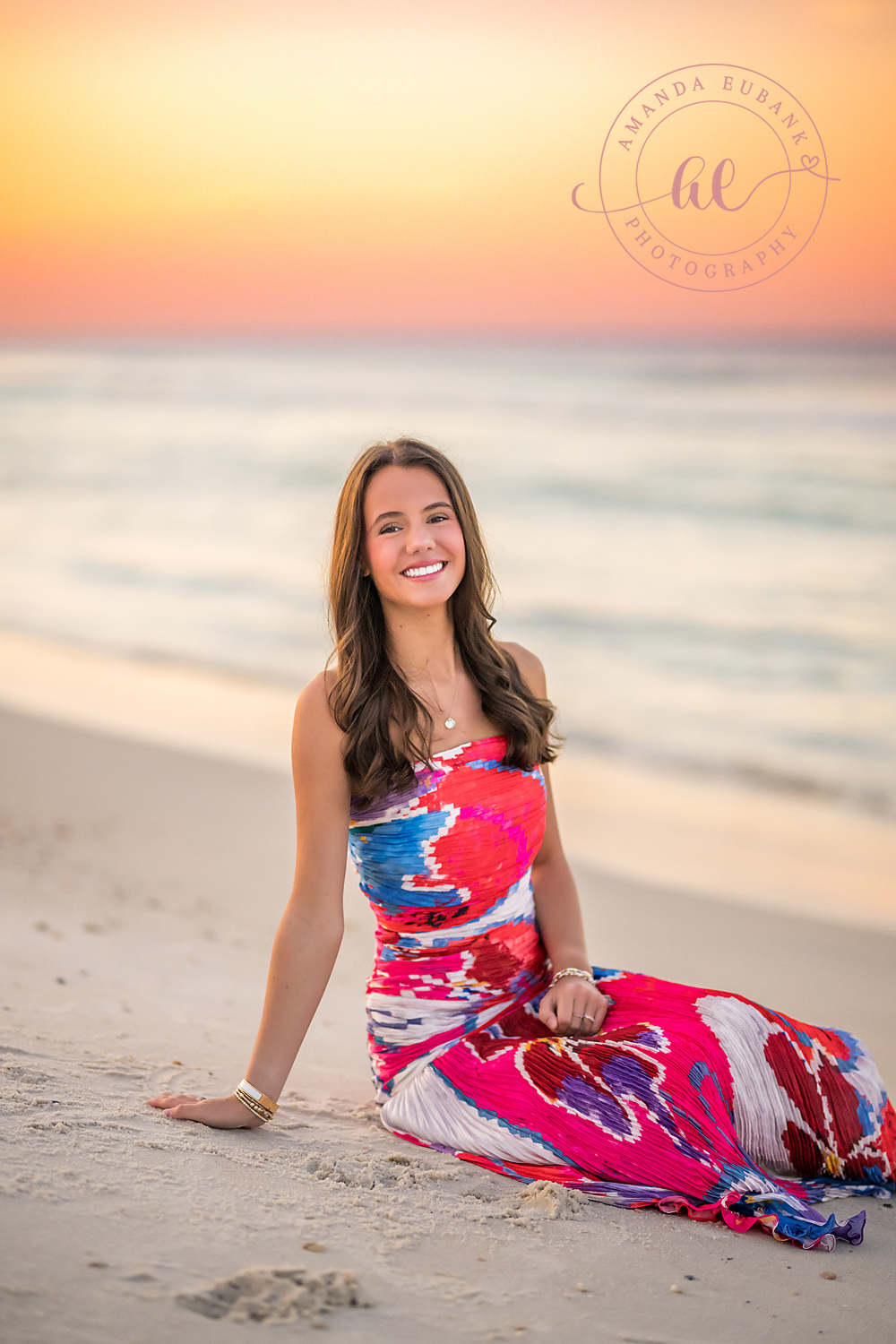 Pink Skirt on the Sand — Tampa Bay Senior Photography A senior in a bright pink patterned skirt seated on the sand at sunset at a beach senior session in Tampa, FL.