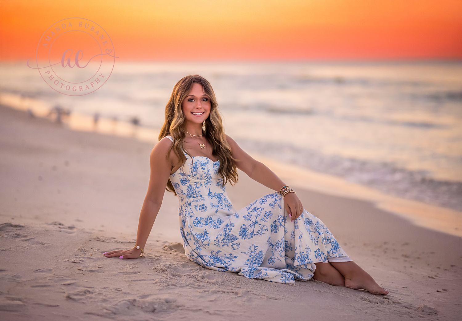 Floral Dress on the Shoreline | Senior Portraits in Tampa, FL Tampa senior photographer captures a senior in a blue floral dress seated on the sand beside the surf.