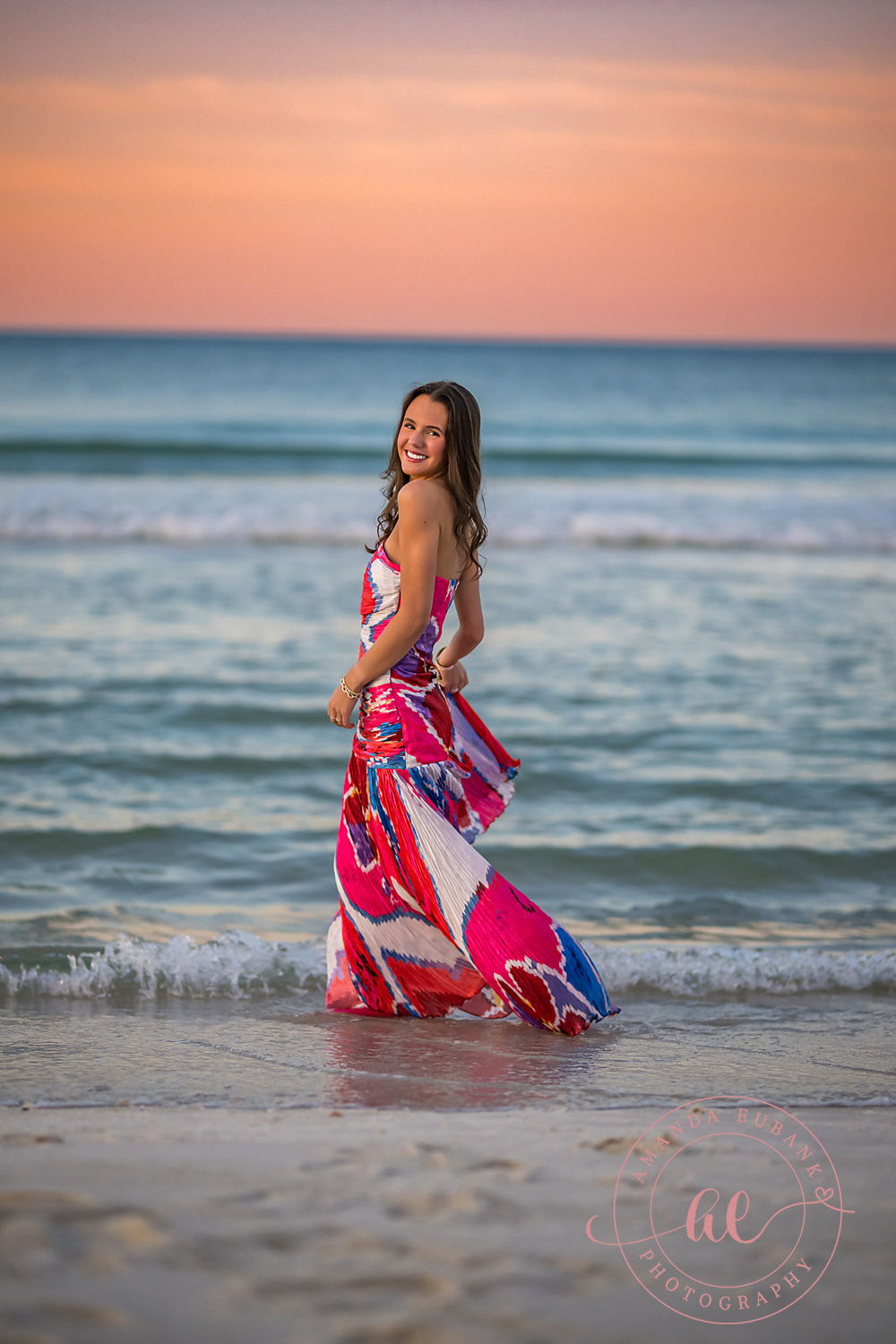 Standing in the Turquoise Shallows | Beach Senior Session in Tampa, Florida Senior pictures in Tampa Bay showing a senior in a pink patterned gown standing in the turquoise shallows.