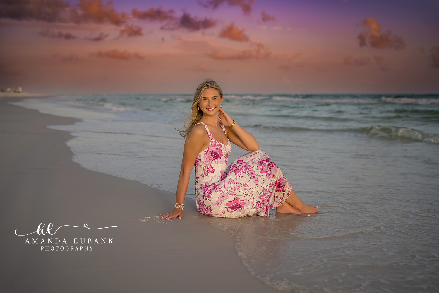 Seated on the Wet Shoreline | Beach Senior Session in Tampa, Florida Senior pictures in Tampa Bay showing a senior in a floral gown seated on the wet shoreline at pastel sunset.