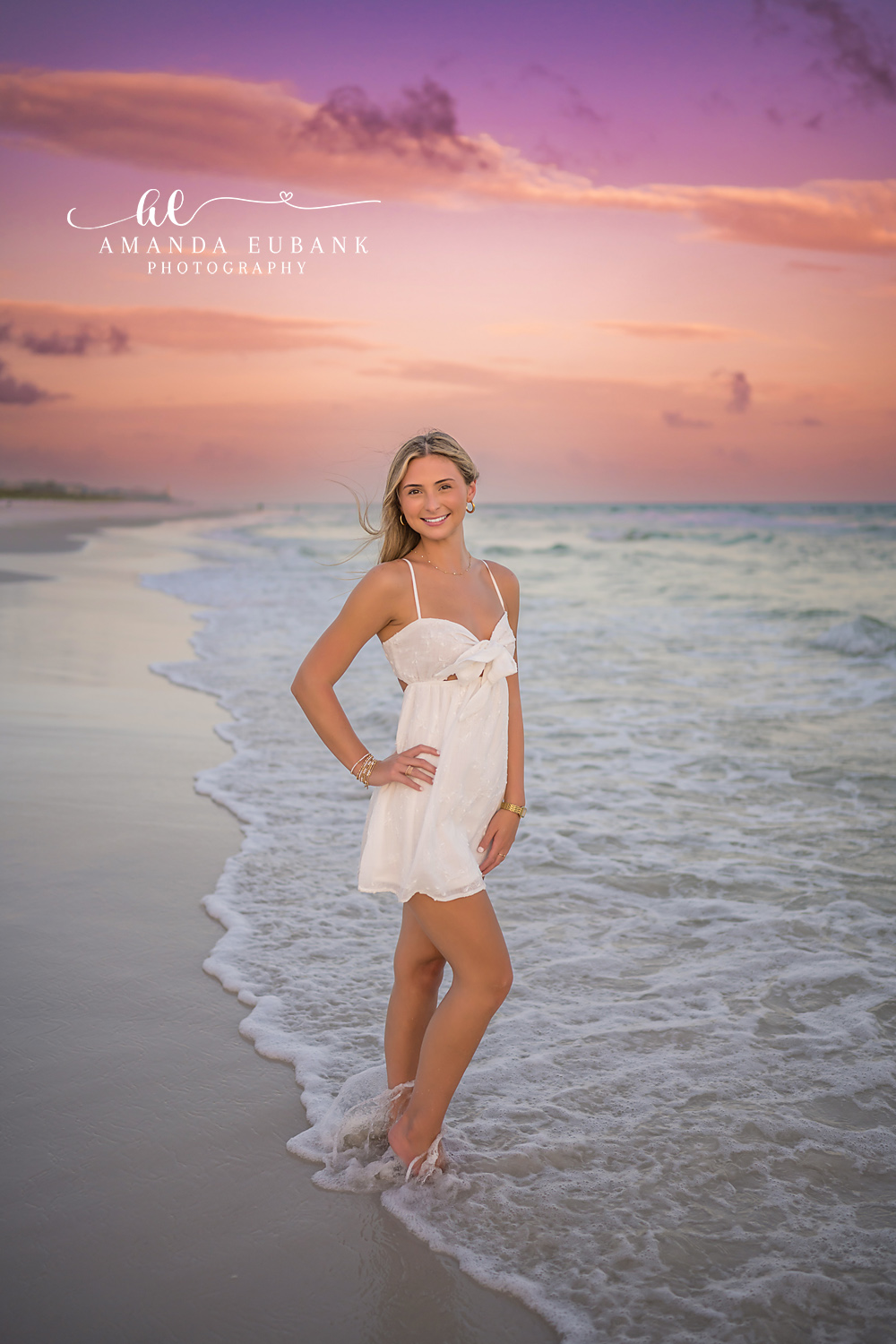 White Dress in the Foam | Senior Portraits in Tampa, FL Tampa senior photographer captures a senior in a short white dress standing in sea foam under a violet sky.
