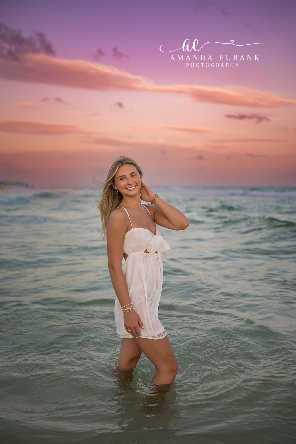 White Dress in the Gulf — Tampa Bay Senior Photography A senior in a white dress standing knee-deep in the Gulf at pastel dusk at a beach senior session in Tampa, FL.
