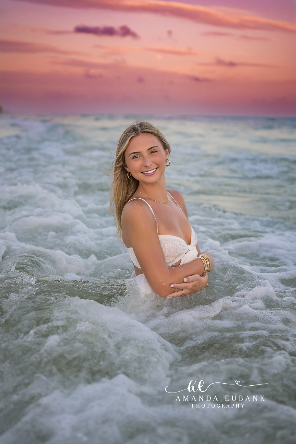 Foam Around Her | Senior Portraits in Tampa, FL Tampa senior photographer captures a senior in a white dress standing in swirling sea foam at pink sunset.