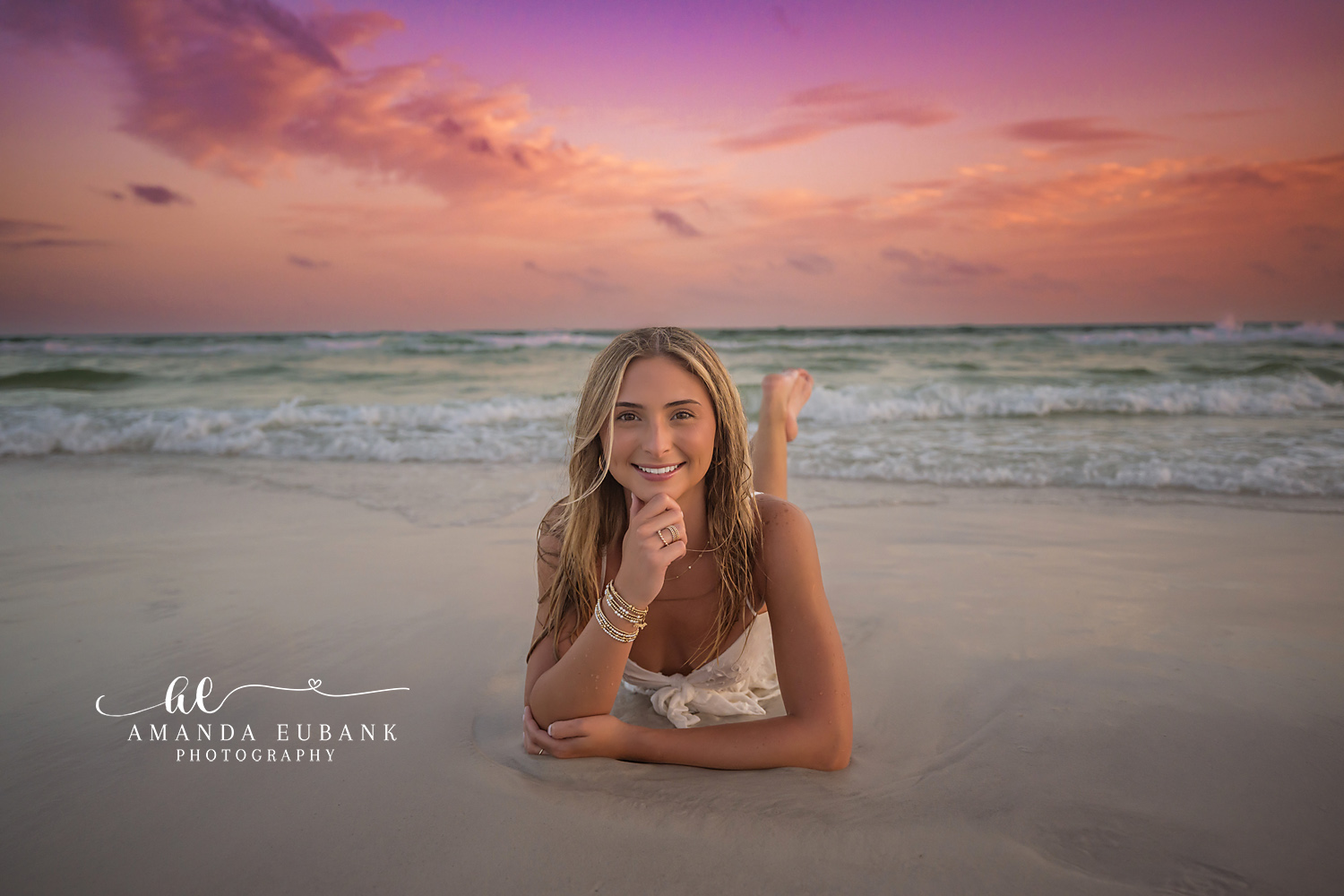 Lying on the Wet Shoreline | Tampa Senior Photographer A senior in a white dress lying on the wet shoreline at violet sunset during a senior portrait session in Tampa, Florida.