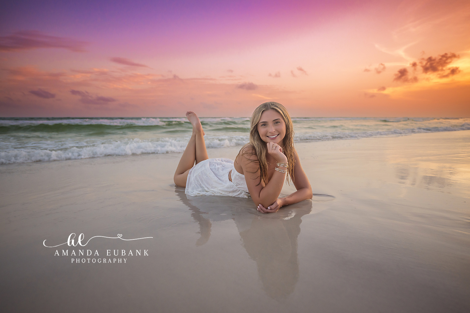 Wet Sand at Golden Hour — Tampa Bay Senior Photography A senior in a white dress lying on mirror-wet sand in golden evening light at a beach senior session in Tampa, FL.