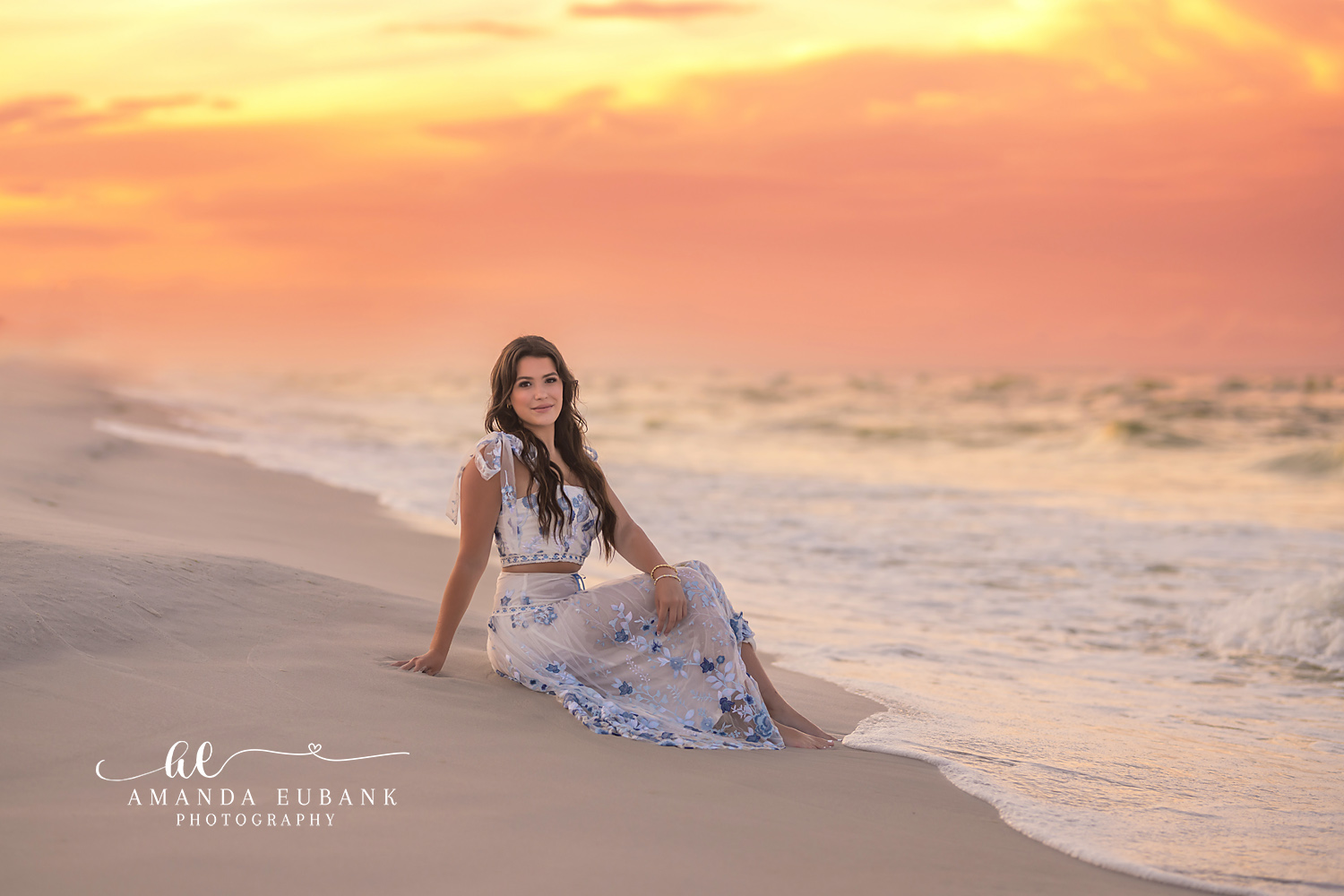Seated Under a Golden Sky | Senior Portraits in Tampa, FL Tampa senior photographer captures a senior in a floral maxi dress seated on the sand beneath a golden sky.