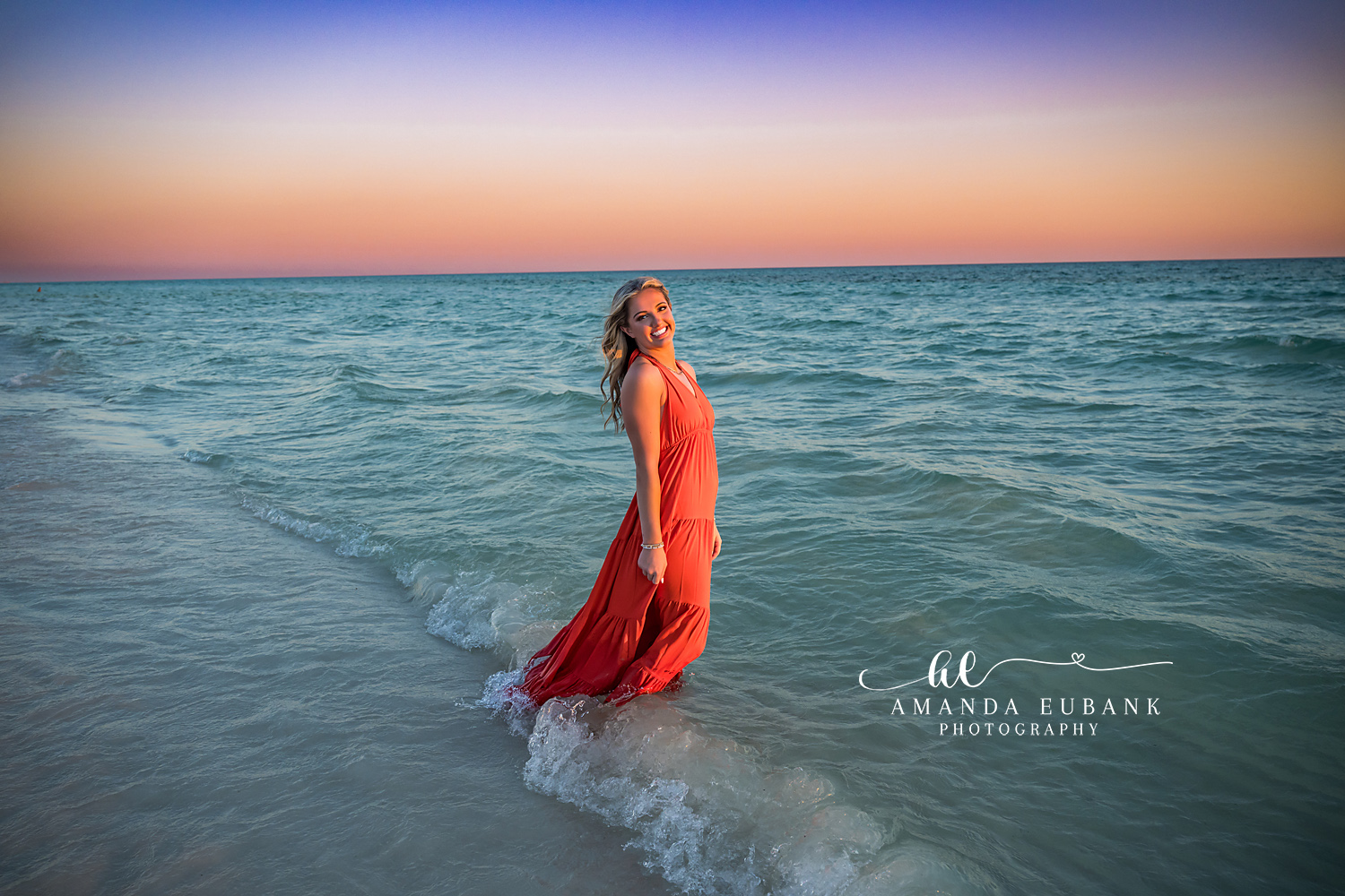 Red Gown in the Sea Foam — Tampa Bay Senior Photography A senior in a red gown standing in the sea foam beneath a lavender sky at a beach senior session in Tampa, FL.