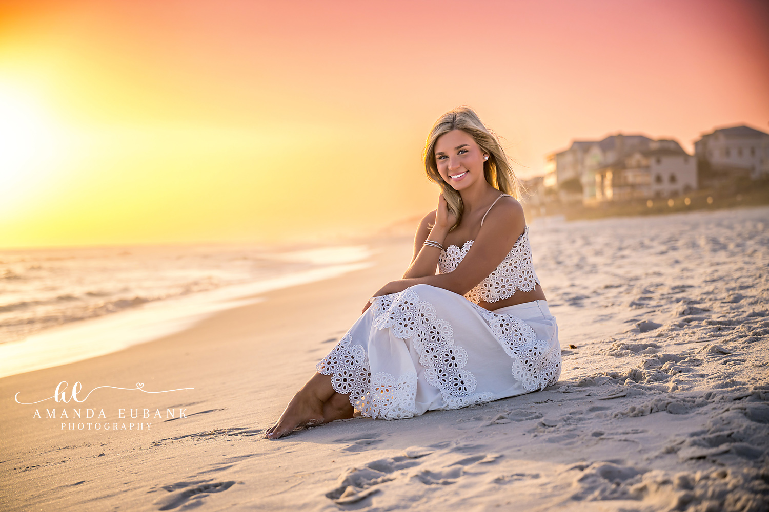 White Dress at Golden Hour — Tampa Bay Senior Photography A senior in a white eyelet dress seated on the sand in warm golden light at a beach senior session in Tampa, FL.