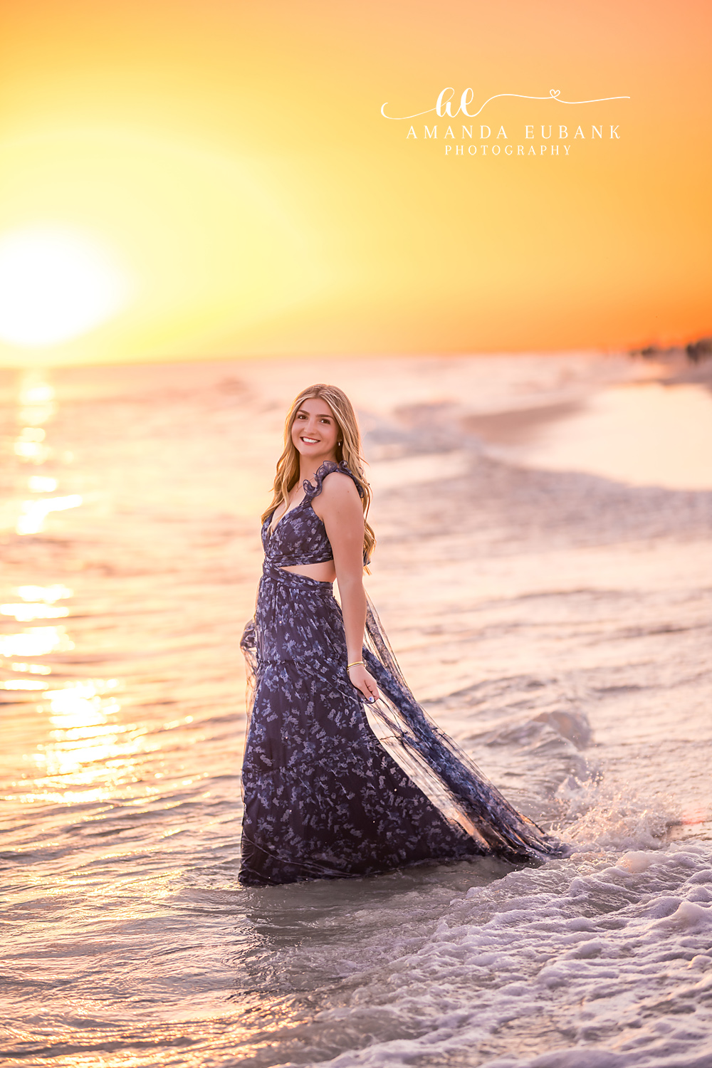 Navy Gown at the Setting Sun | Senior Portraits in Tampa, FL Tampa senior photographer captures a senior in a navy gown standing in the surf as the sun sets behind her.