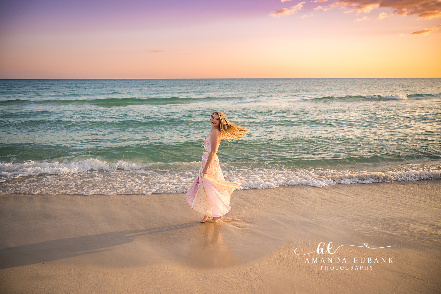Blush Gown in the Shallows | Beach Senior Session in Tampa, Florida Senior pictures in Tampa Bay showing a senior in a blush gown standing in the shallows beneath a soft pastel sky.