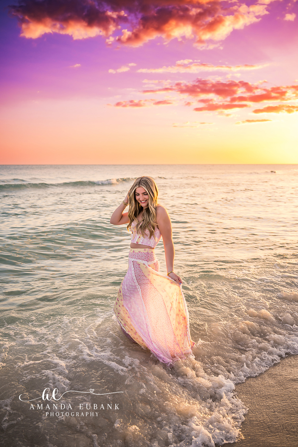 Blush Gown Under Violet Clouds | Senior Portraits in Tampa, FL Tampa senior photographer captures a senior in a blush gown in the surf beneath violet and coral clouds.