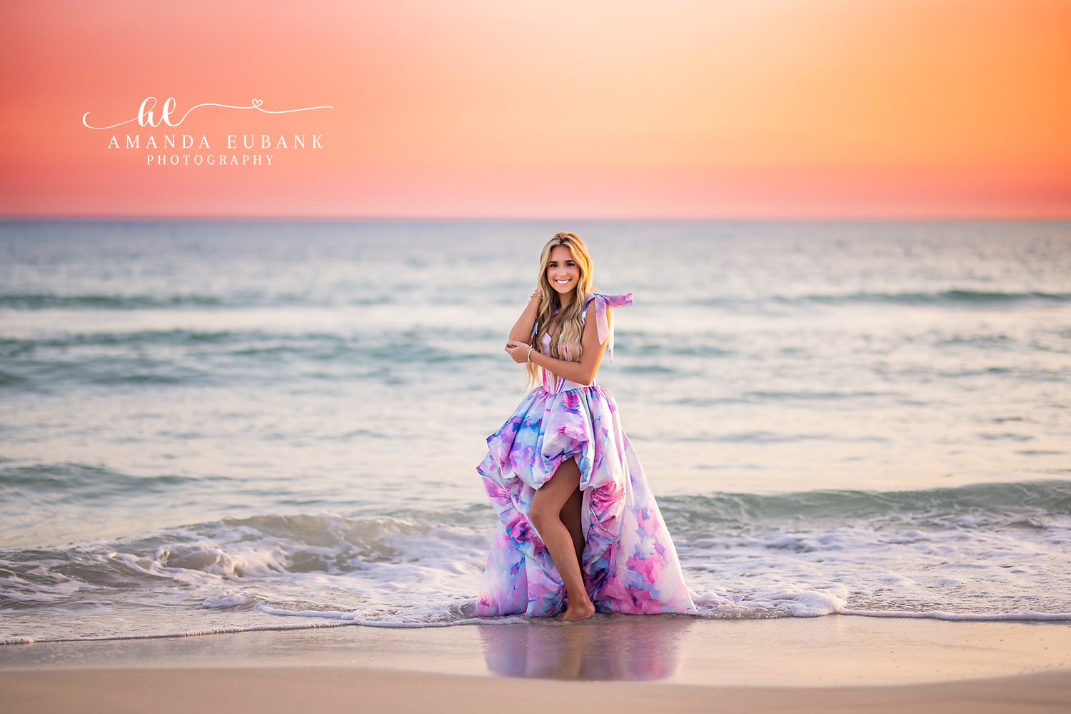 Watercolor Gown at Sunset | Beach Senior Session in Tampa, Florida Senior pictures in Tampa Bay showing a senior in a watercolor-print gown standing in the shallows at coral sunset.