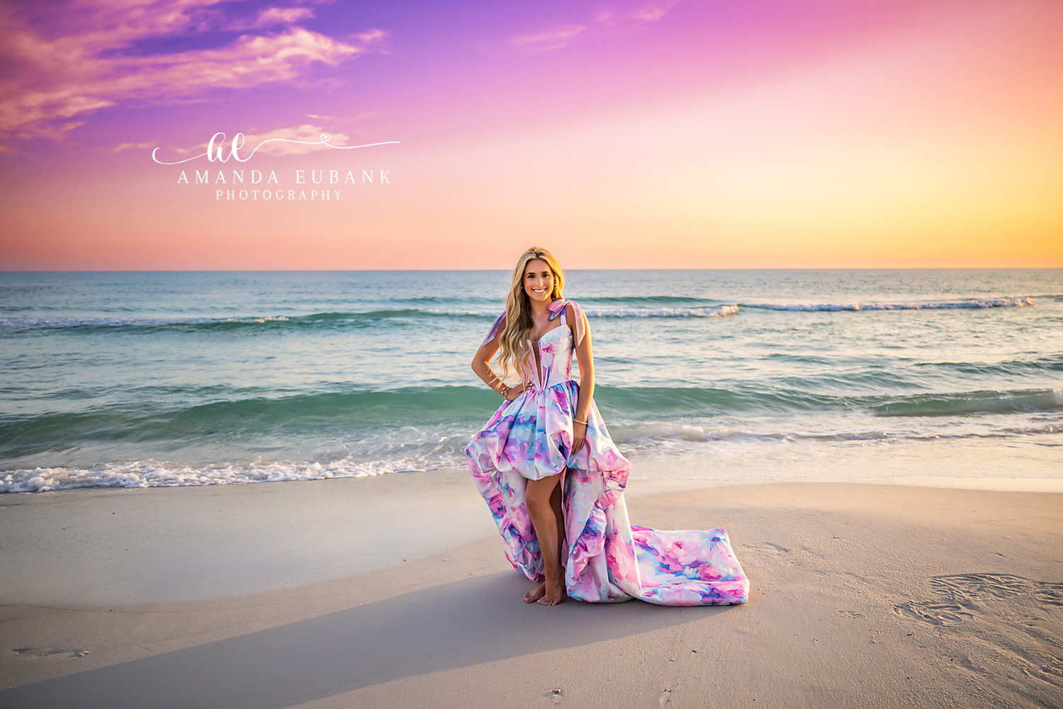 Standing in the Shallows at Dusk | Beach Senior Session in Tampa, Florida Senior pictures in Tampa Bay showing a senior in a printed gown standing in the shallows beneath a violet sky.